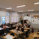 Uczniowie w klasie siedzą w ławkach i robią serca z rąk do zdjęcia..jpg