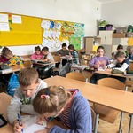 Uczniowie w klasie siedzą w ławkach i wypłeniają kartki.jpg