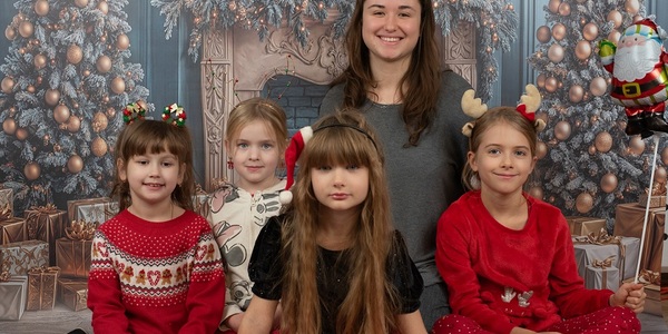 Cztery dziewczynki razem z panią na tle świątecznej dekoracji.
