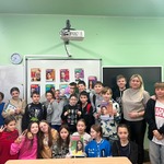 Grupa uczniów stoi z nauczycielką w klasie . Niektóre osoby trzymają plakaty w rękach..jpg
