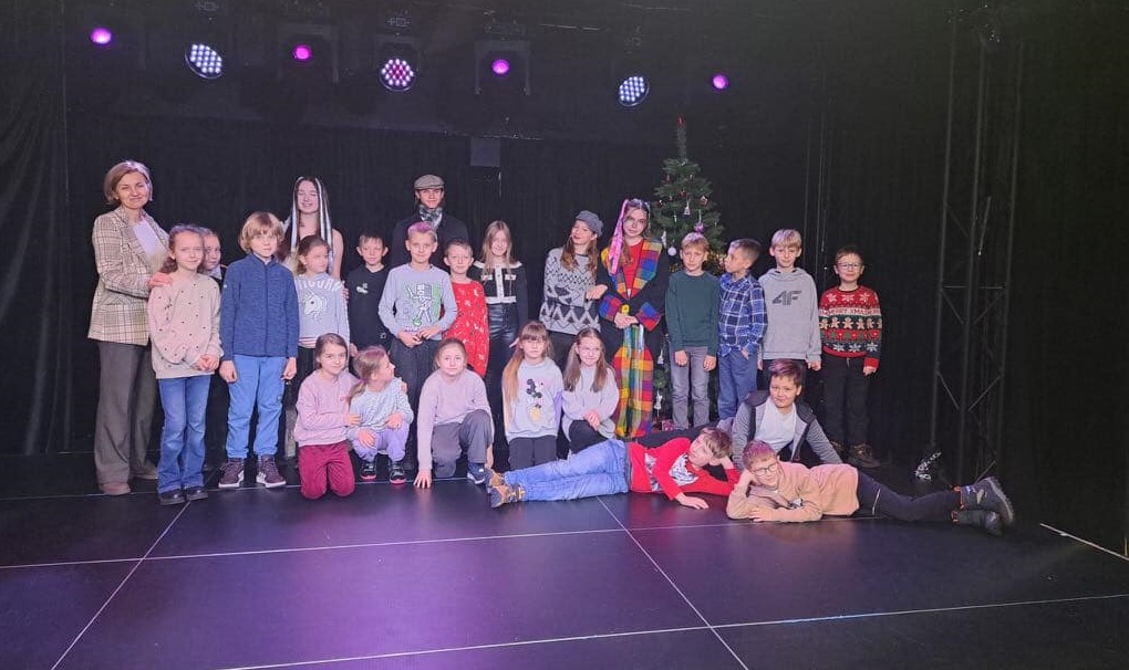 Grupa dzieci razem z nauczycielką stoi na scenie teatru..jpg