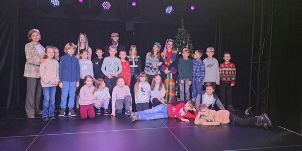 Grupa dzieci razem z nauczycielką stoi na scenie teatru..jpg