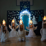 Dziewczynki przebrane za aniołków siedzą z lampionami.