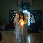Dziewczynki przebrane za aniołków tańczą z lampionami.