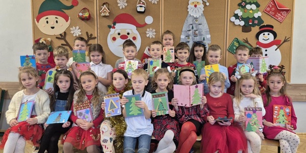 Uczniowie ubrani w świąteczne stroje trzymają kartki świateczne.jpg