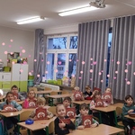 Uczniowie siedzą w ławkach w klasie i trzymają w rękach książki..jpg