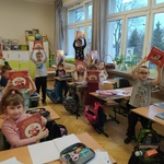 Uczniowie stoją i siedzą  w klasie_ trzymają w rękach w górze książki..jpg