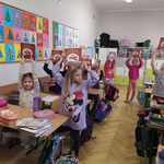 Uczniowie stoją w klasie i trzymają w rękach w górze książki..jpg