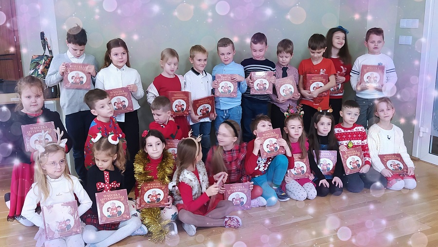 Grupa dzieci pozuje do zdjęcia z książkami w rękach.jpg