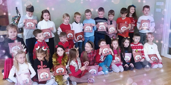 Grupa dzieci pozuje do zdjęcia z książkami w rękach.jpg