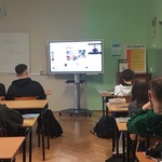 Uczniowie w klasie siedzą na przeciwko monitoru..jpg