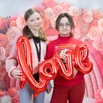 Dwie dziewczynki trzymają napis love na tle różowych kwiatów