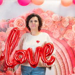 Kobieta trzyma w rękach napis love na tle różowych kwiatów