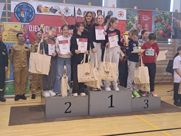 Grupa dziewczyn stoi na podium z dyplomami i upominkami.jpg