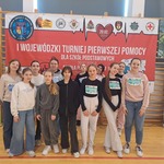Grupa uczennic stoi na tle billboardu z napisem pierwsza pomoc..jpg