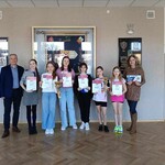 Uczennice wraz z dyrektorem i nauczycielką stoją na tle sztandaru szkoły.jpg