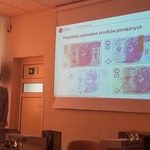 Kobieta stoi przy ekranie z banknotami..jpg